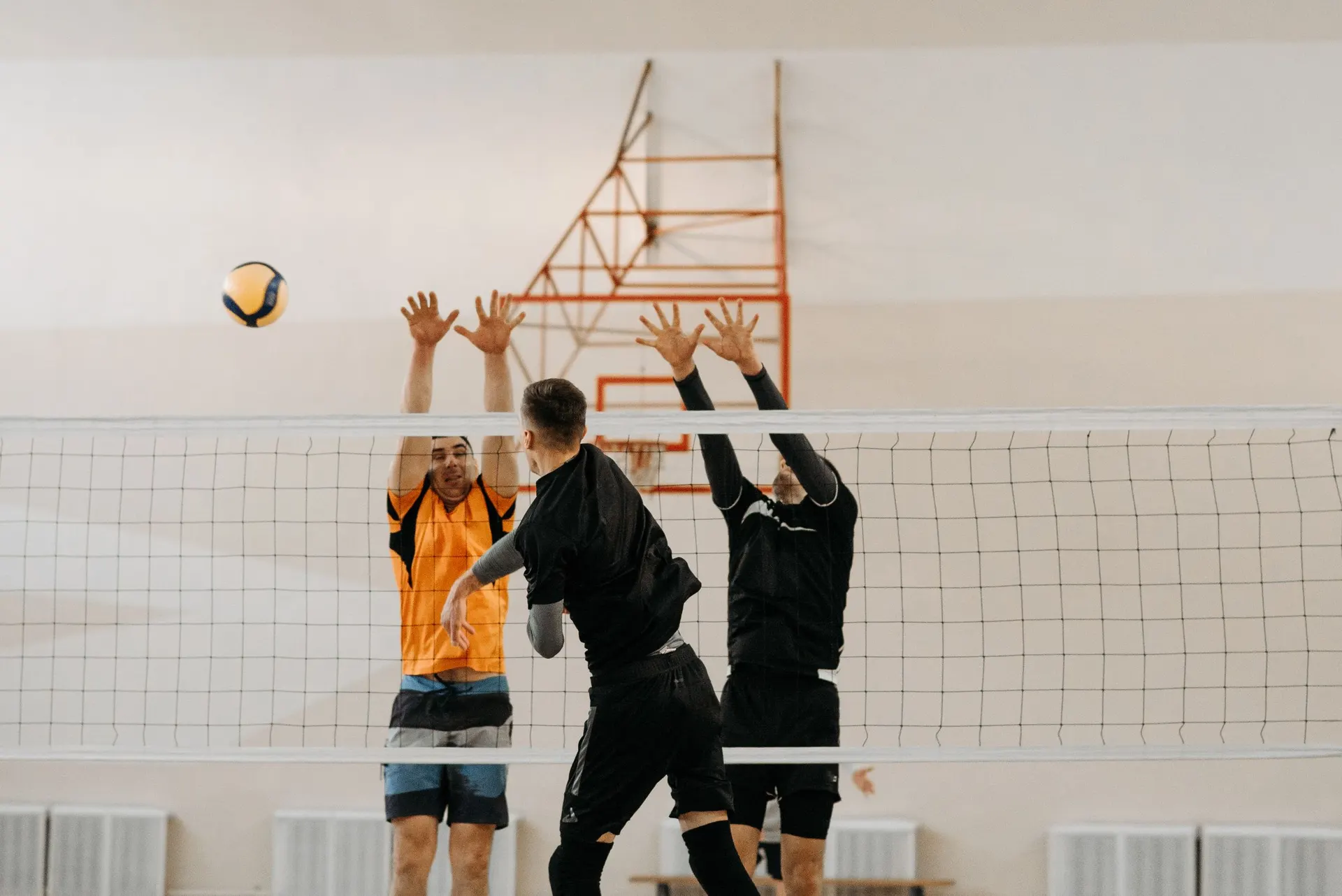 Two volleyball players jumping to block at the net