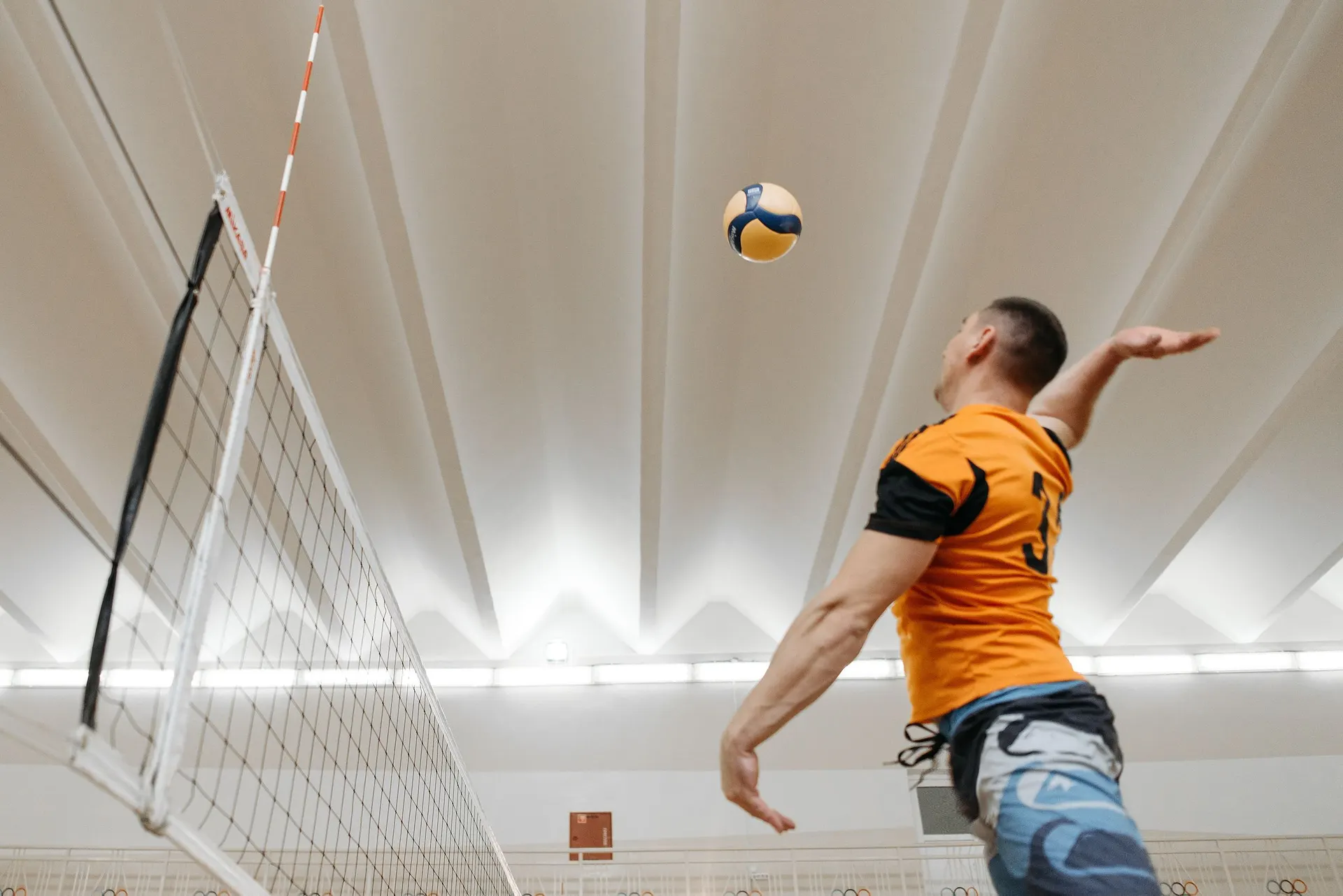 Volleyball player leaping to spike the ball at the net