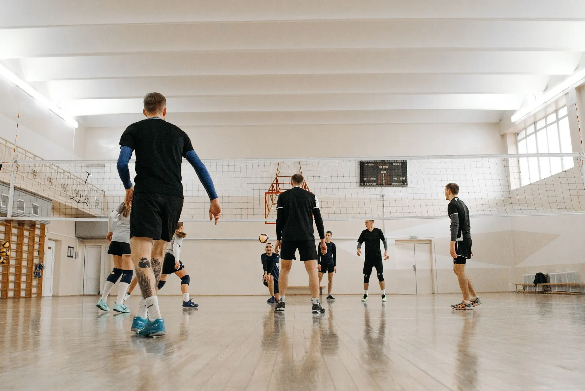 Volleyball team training at the net in a bright indoor hall