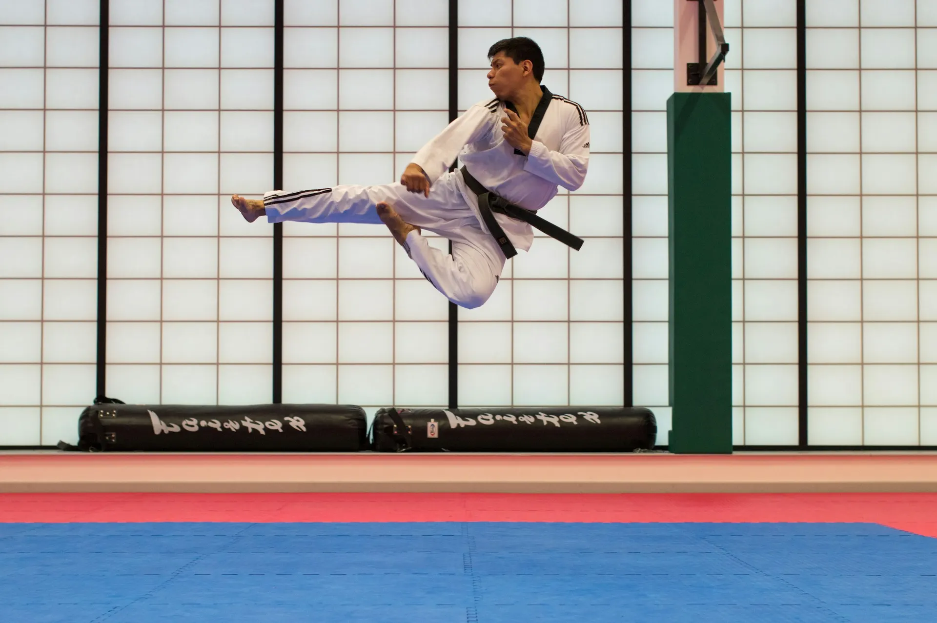 Taekwondo athlete performing a flying side kick in the training hall