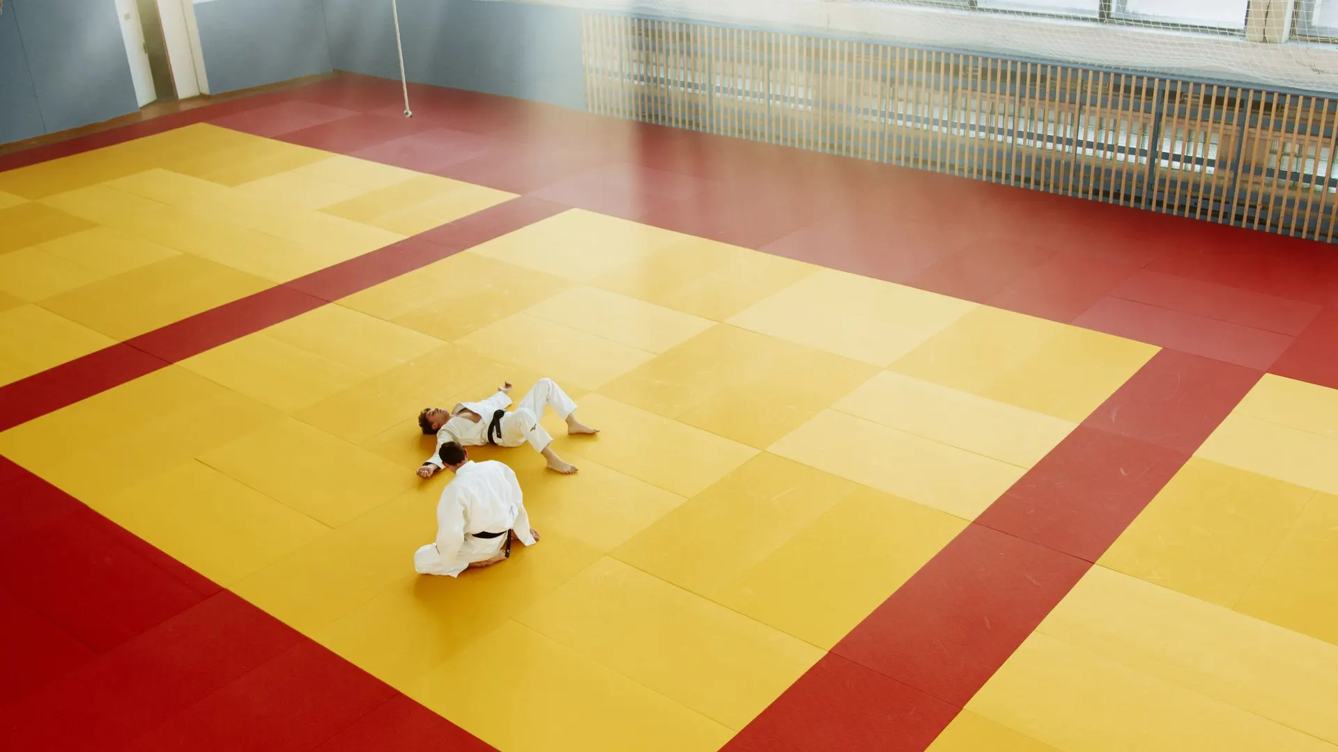Large training hall covered in red and yellow tatami mats